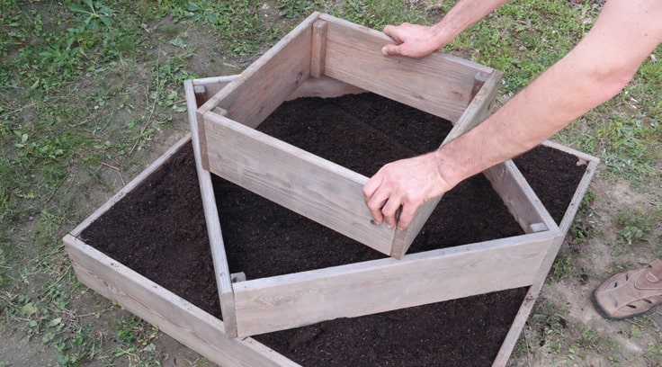 Auf den zweiten Holzrahmen folgt diagonal der dritte. Dadurch entstehen wieder Ecken – wobei diesmal nur jeweils eine Saatkartoffel in jede Ecke gelegt wird.