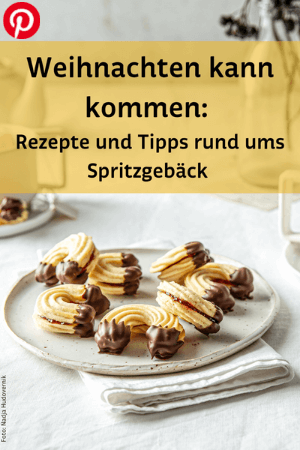 Teller mit Spritzgebäck, Kaffeetassen und Vase am Tisch