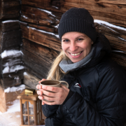 Frau auf Holzbank vor Almhütte im Winter