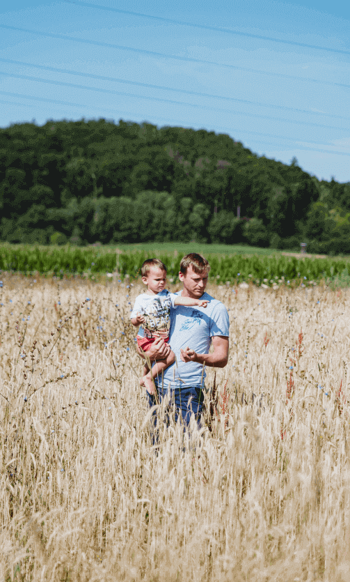 Mann mit Kind am Arm im Feld