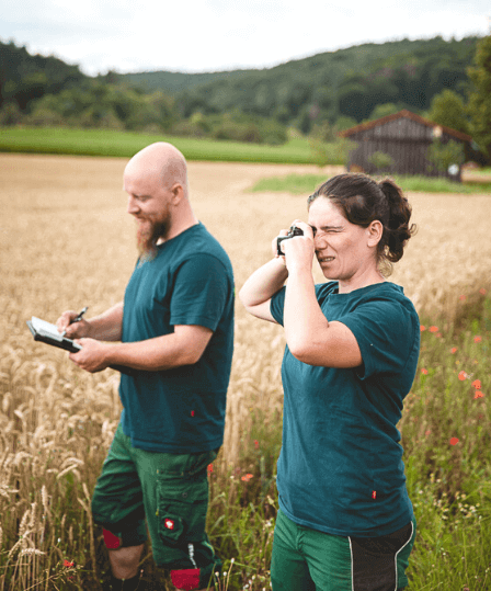 Mann und Frau mit Block und Fernglas im Feld