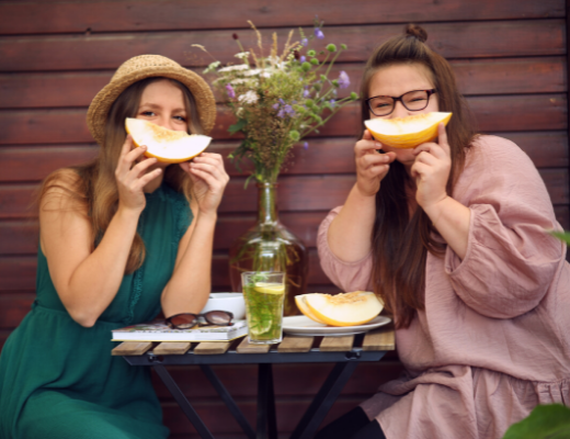 zwei Frauen mit Melone vor dem Gesicht