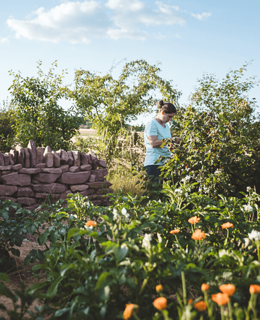 Frau im Garten am Rand eines Feldes