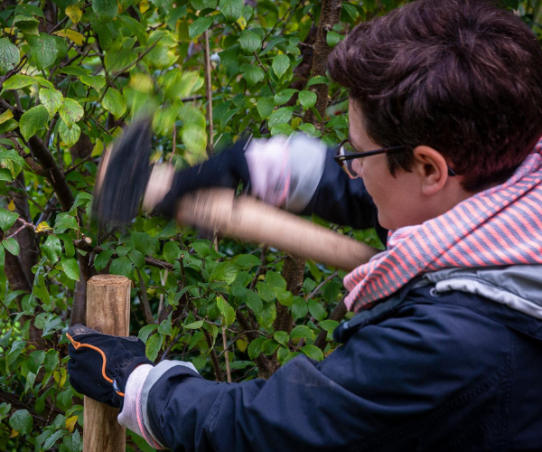 Deborah Hucht arbeitet im Garten mit einem Hammer.